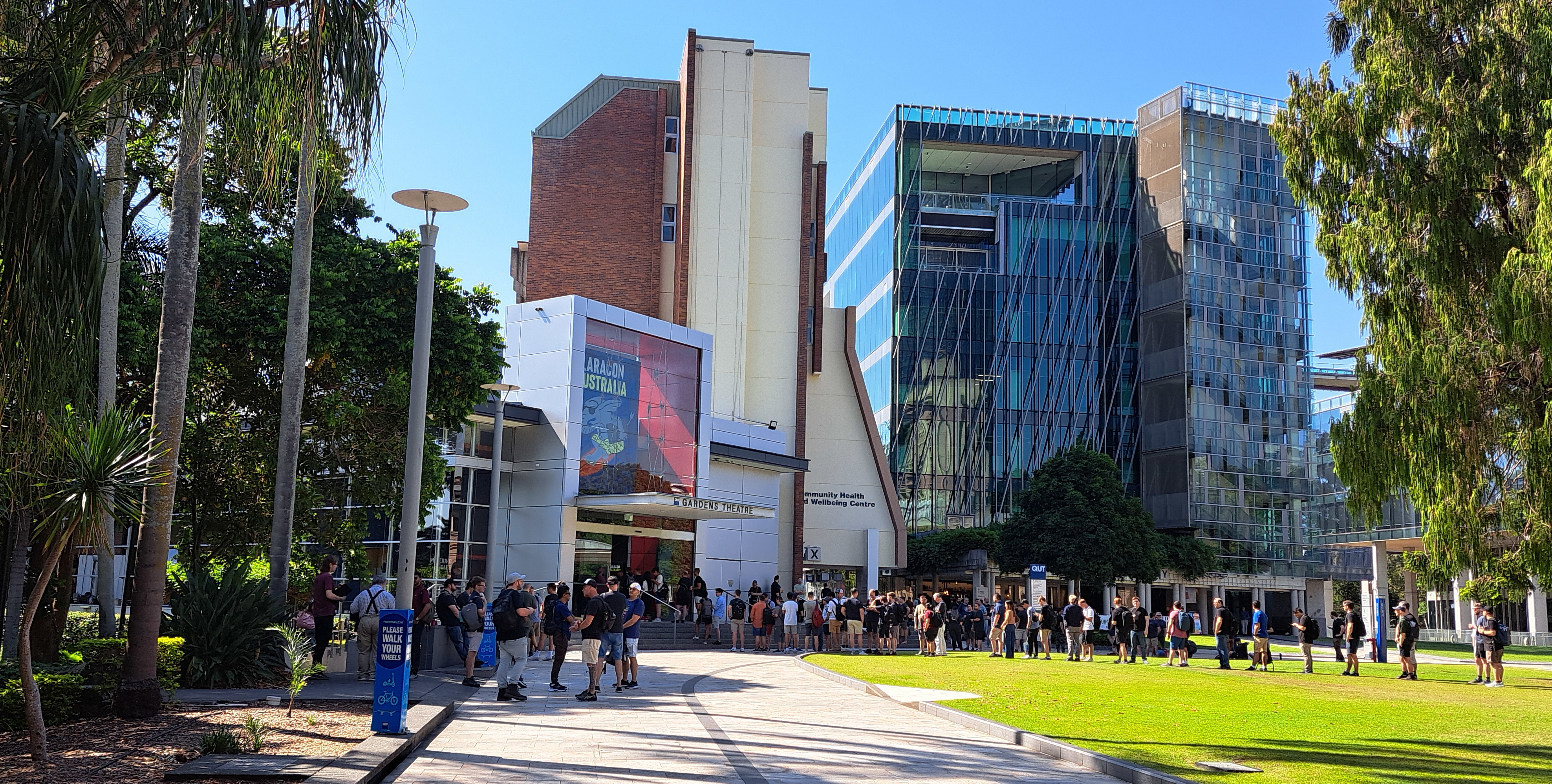 Arriving at QUT Gardens Theatre, the Laracon AU 2024 venue. The theatre is up the path ahead, and a large crowd of attendees is standing out the front.